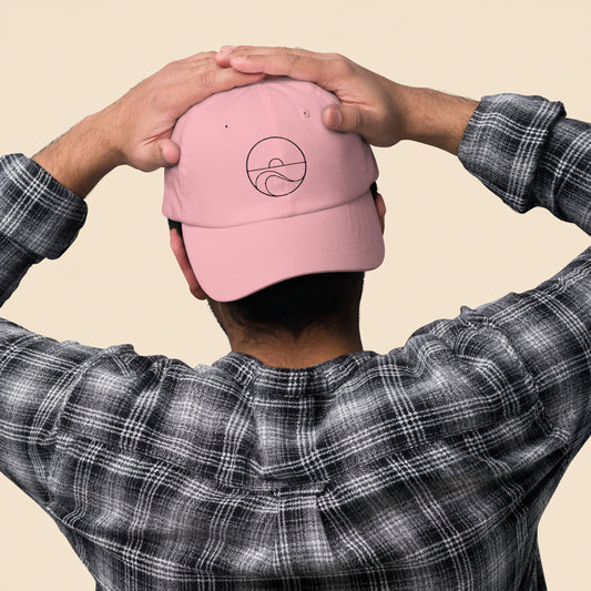 Hombre de espaldas con camisa de cuadros luciendo la gorra dad hat rosa, mostrando el cierre ajustable.
