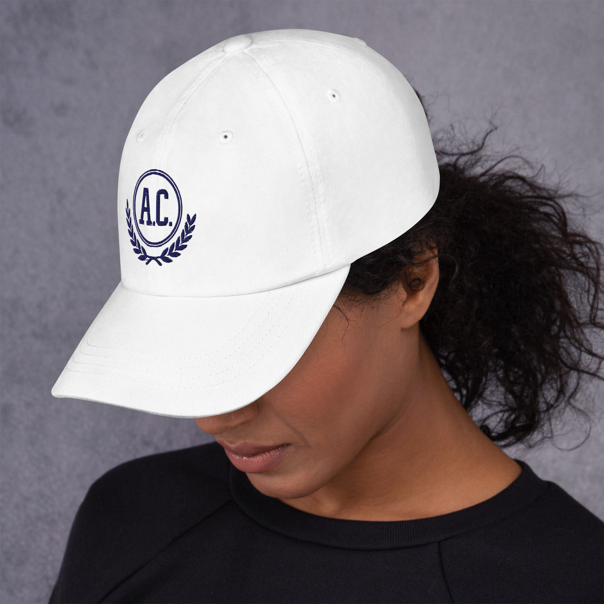 Primer plano de mujer mirando hacia abajo vistiendo gorra blanca de sarga de algodón con emblema bordado A.C.