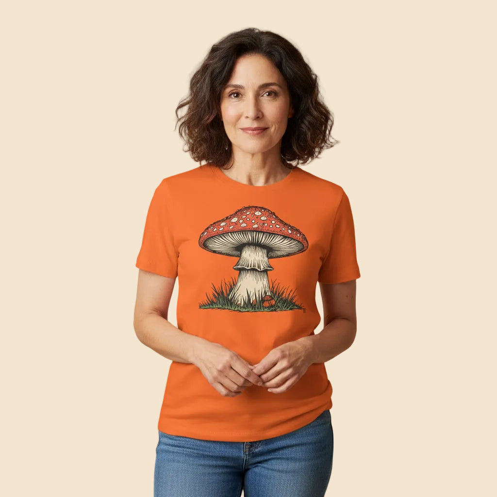 Mujer con estilo urbano vistiendo una camiseta naranja de manga corta y diseño cottagecore de la naturaleza.