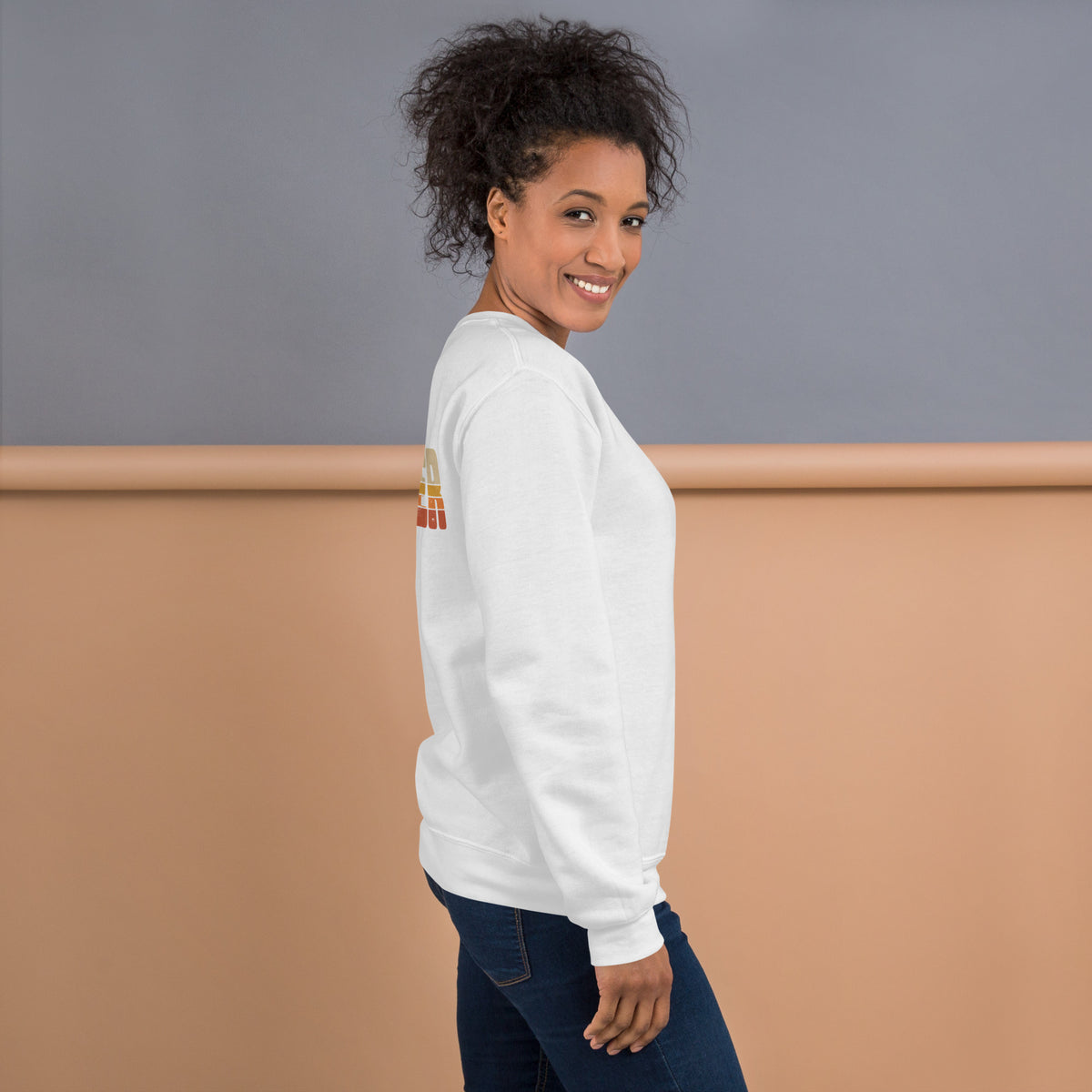 Mujer de perfil vistiendo sudadera blanca básica con diseño retro en la espalda.