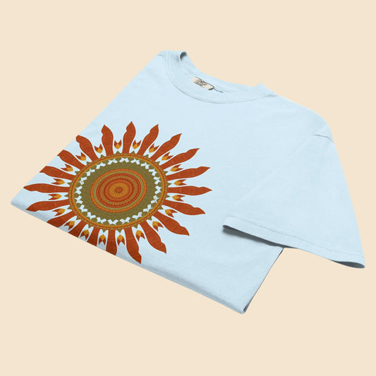 Camiseta azul claro doblada mostrando el detalle y la textura del diseño de sol vintage en colores calidos.