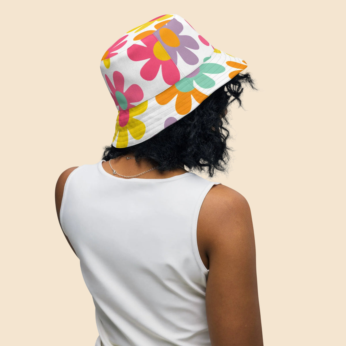 Persona llevando gorro bucket unisex reversible con diseño All Over Print de inspiración retro y colores arcoíris.