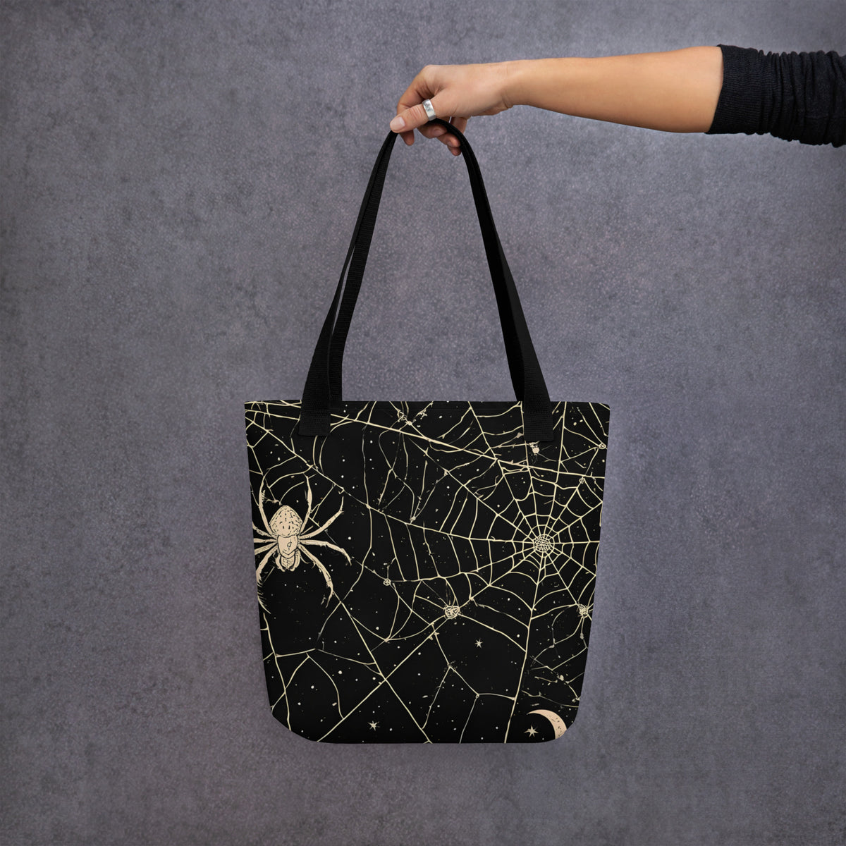 Bolsa de tela negra con estampado vintage de telarañas, araña, luna y estrellas llevada por una persona