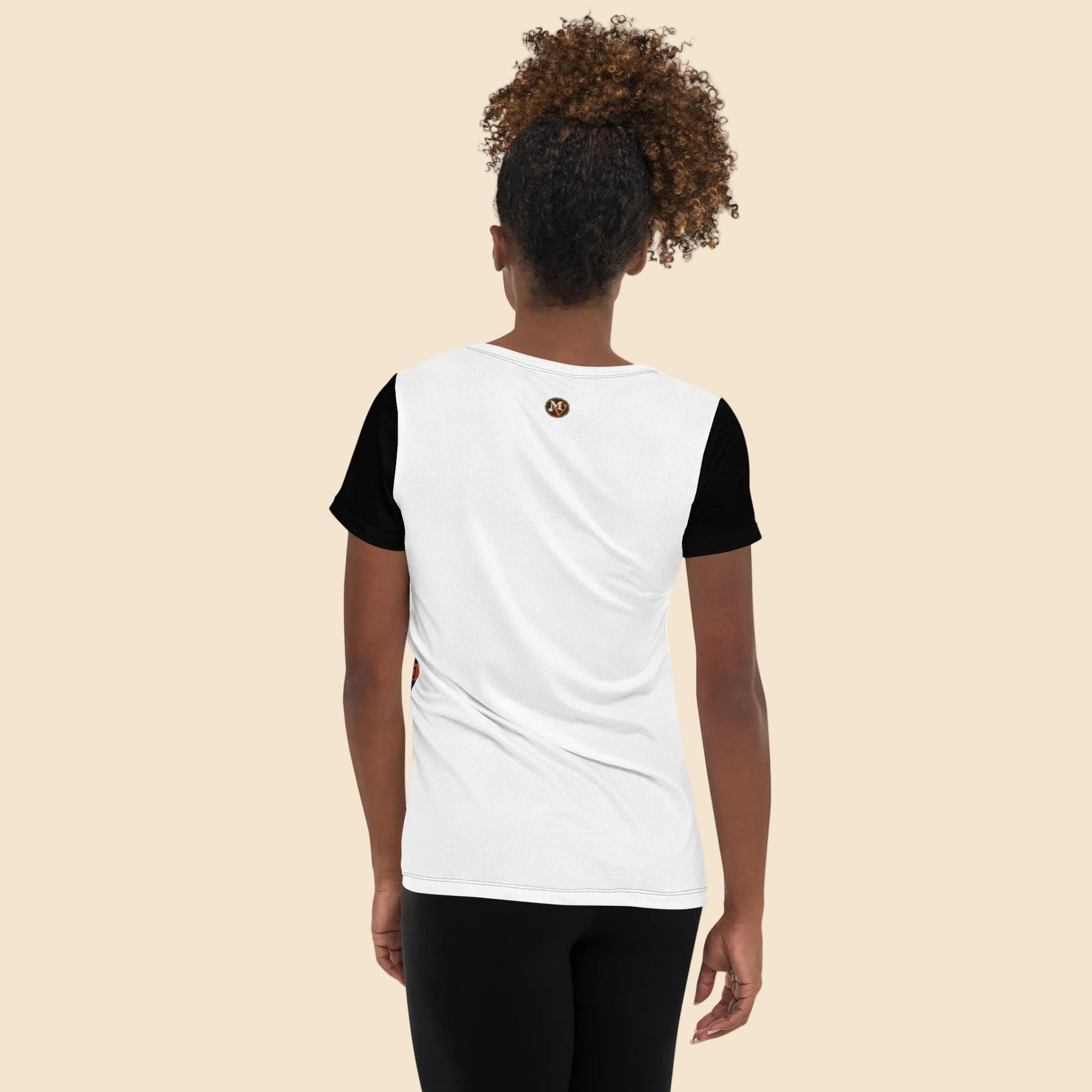 Vista trasera de modelo femenina luciendo una camiseta premium de corte ajustado, destacando el contraste de las mangas negras con la espalda clara.