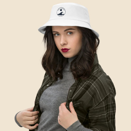 Mujer vistiendo gorro de pescador blanco de estética surfera con ilustración clásica de ola y sol.