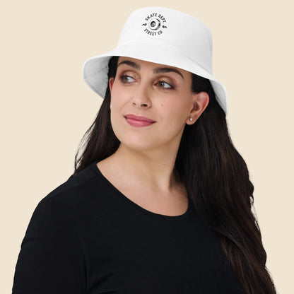 Mujer vistiendo gorro bucket color blanco de estilo urbano con emblema skater clásico.