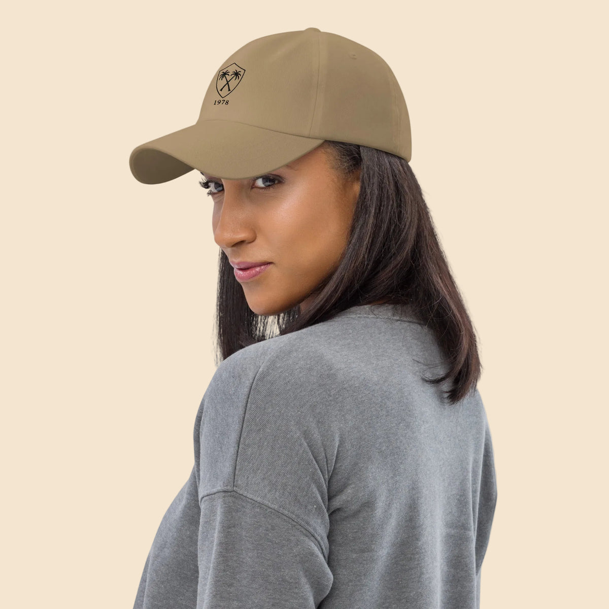  Mujer mirando por encima del hombro vistiendo gorra dad hat caqui de estilo resort vintage.