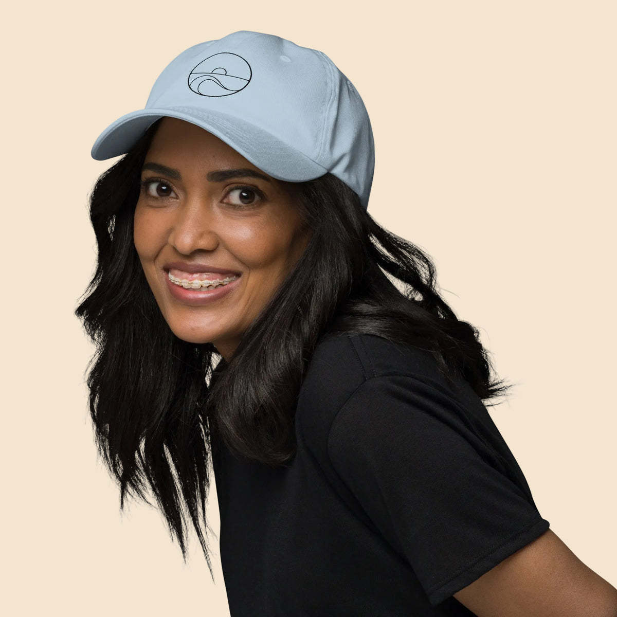 Mujer sonriente luciendo la gorra dad hat de algodón en color azul claro.