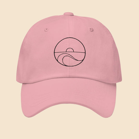 Gorra dad hat de sarga de algodón en color rosa con diseño minimalista bordado de sol y olas del mar en color negro.