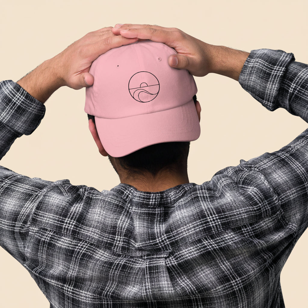 Hombre de espaldas con camisa de cuadros luciendo la gorra dad hat rosa, mostrando el cierre ajustable.