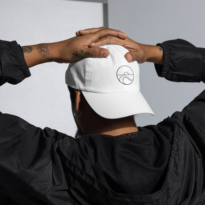 Hombre de espaldas ajustándose a la cabeza una gorra dad hat en color blanco.