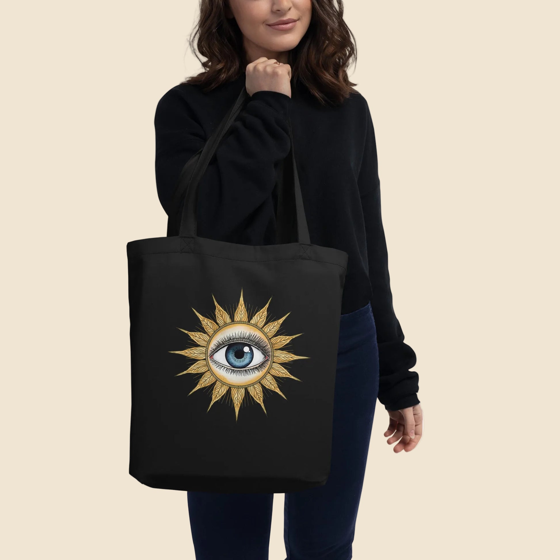 Mujer vistiendo de negro llevando al hombro una bolsa de tela tote bag con ilustración esotérica y bohemia.