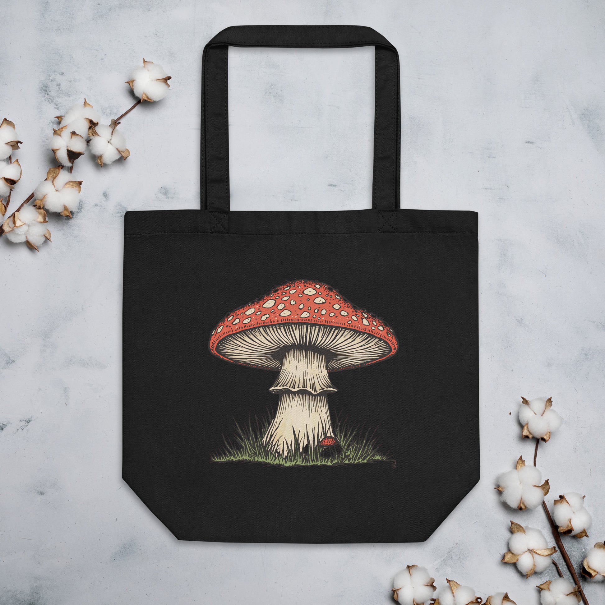 Bolsa de tela negra con gráfico de seta vintage apoyada sobre una superficie plana junto a elementos decorativos florales y naturales.