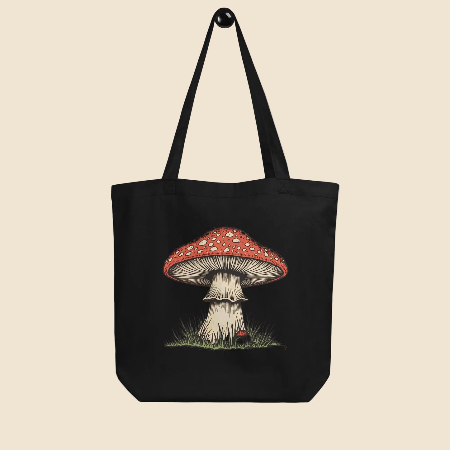 Bolsa de tela tote bag negra de algodón orgánico con diseño frontal de ilustración botánica de seta amanita.