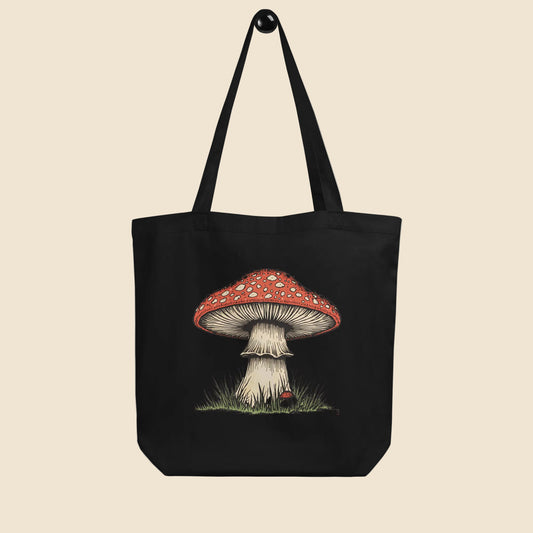 Bolsa de tela tote bag negra de algodón orgánico con diseño frontal de ilustración botánica de seta amanita.