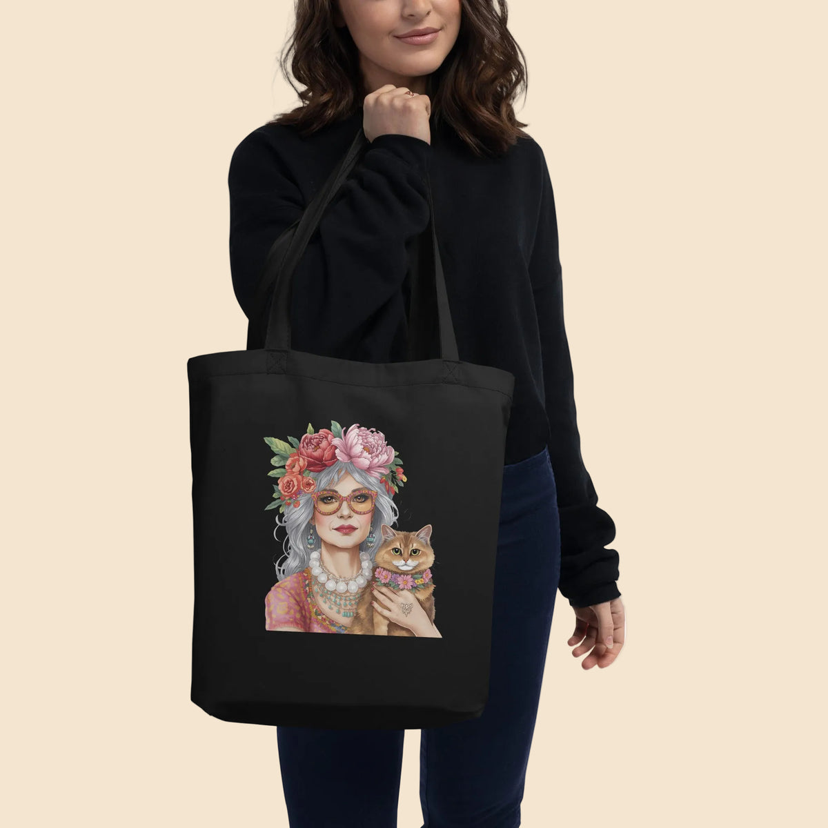 Persona llevando una bolsa de algodón negro con ilustración de mujer boho y gato rodeados de flores