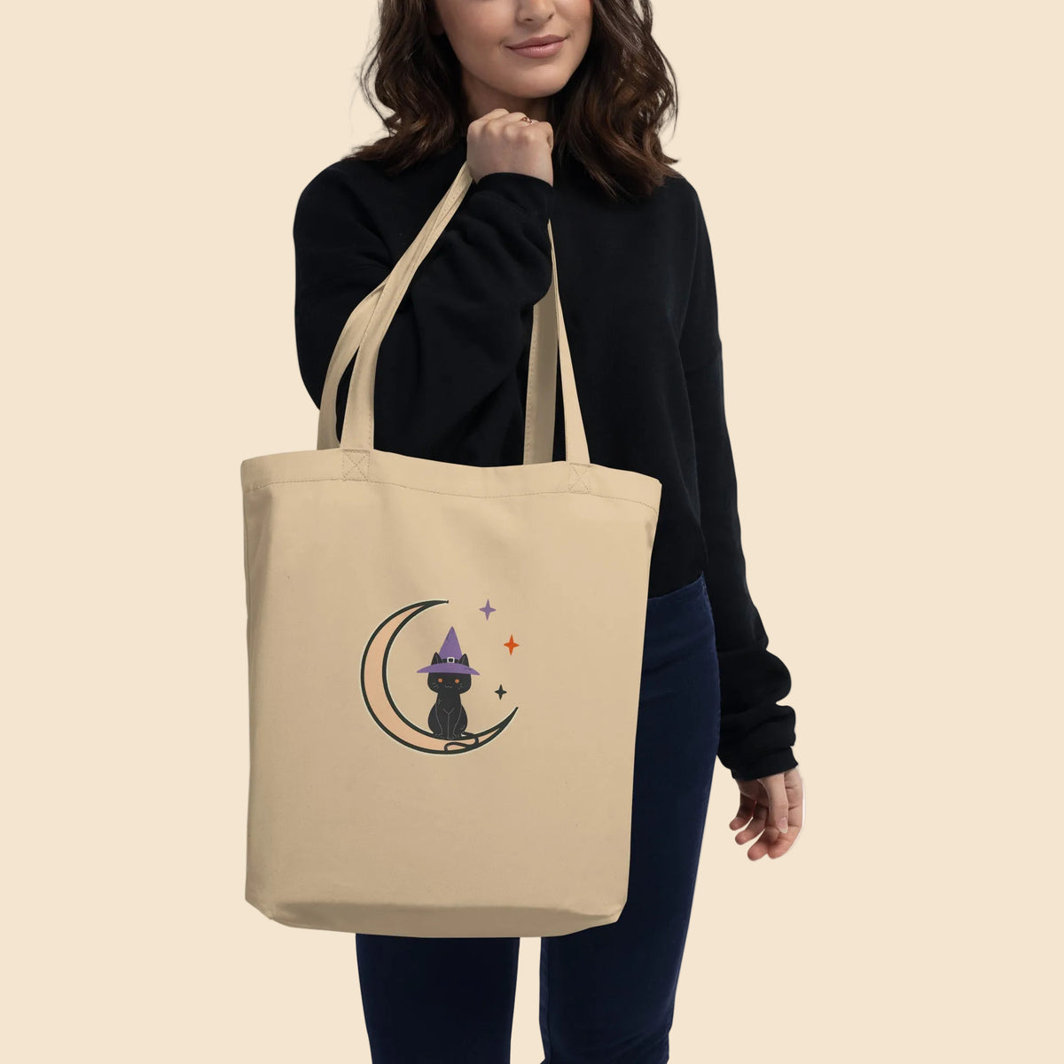 Mujer llevando una bolsa de algodón orgánico con diseño vintage de gato negro sobre una luna creciente