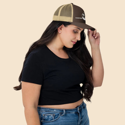 Mujer de perfil vistiendo gorra trucker marrón y caqui mostrando el cierre snapback y la malla trasera transpirable.