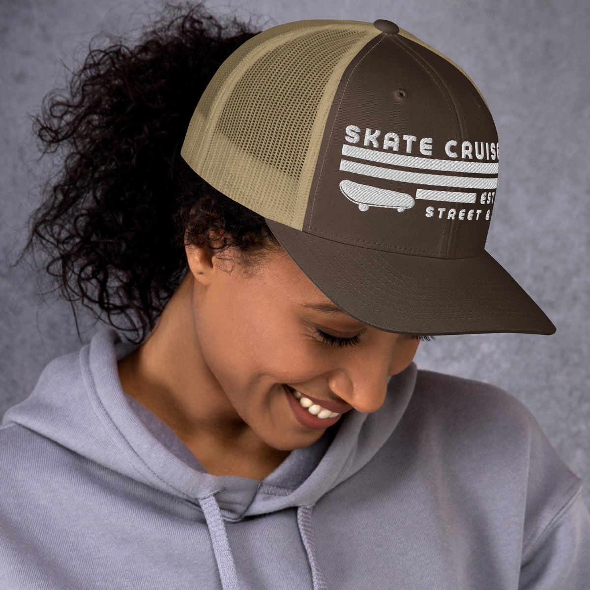 Mujer mirando hacia abajo vistiendo gorra trucker marrón y caqui de estilo retro skater.