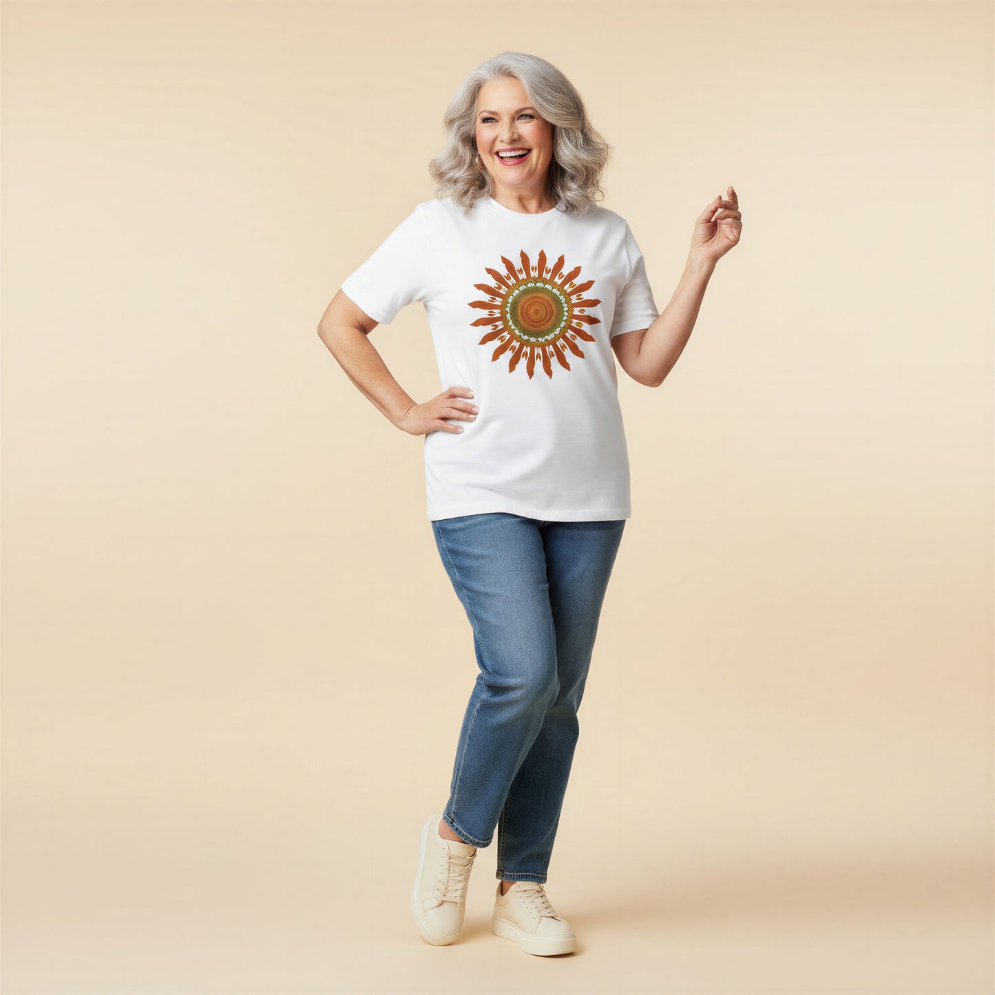 Mujer de pelo canoso sonriendo y luciendo una camiseta blanca de corte holgado con estampado de sol retro.
