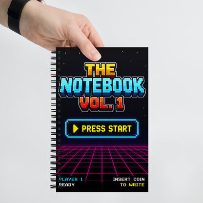 Persona sujetando una libreta gamer vintage con diseño inspirado en máquinas recreativas clásicas.