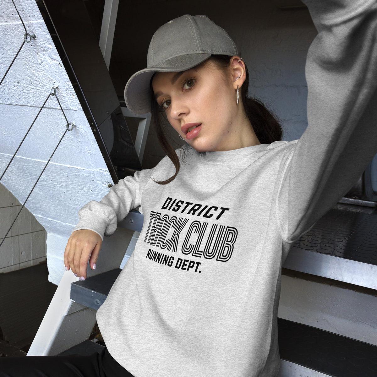 Mujer con gorra luciendo sudadera color ceniza de estética streetwear y diseño de atletismo.