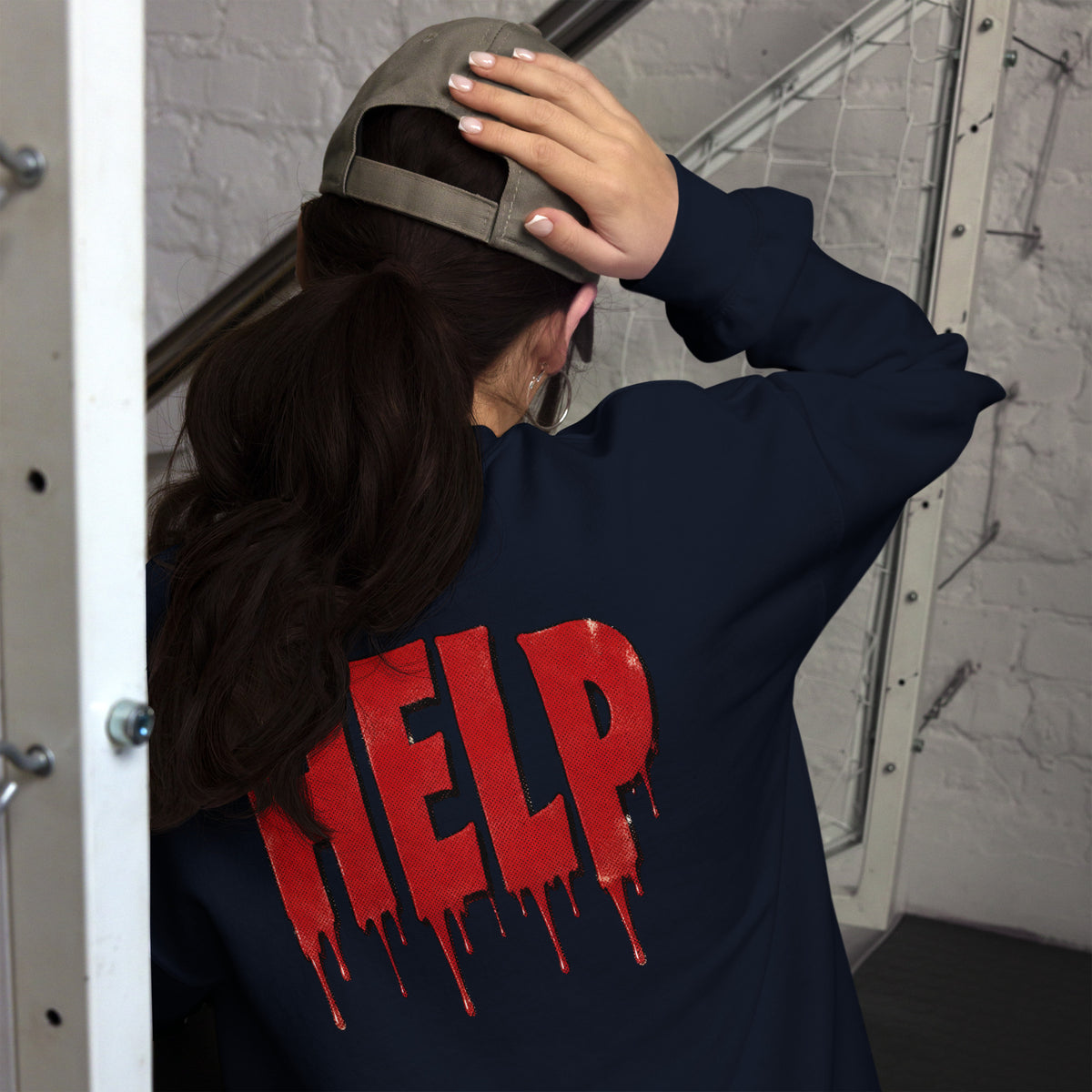 Persona con sudadera azul marino HELP ajustándose la prenda en un ambiente oscuro