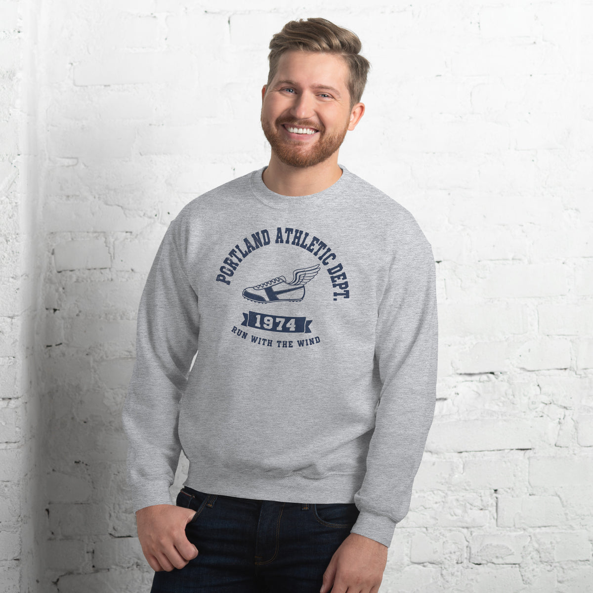  Hombre sonriendo con sudadera gris y diseño clásico de atletismo.