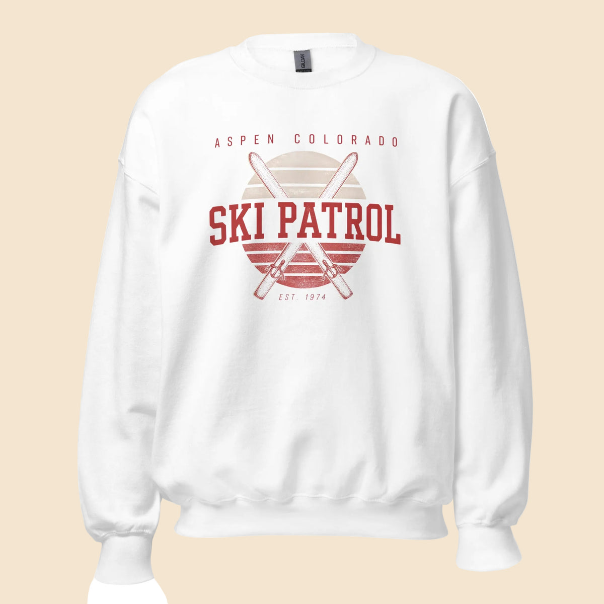 Sudadera unisex de cuello redondo en color blanco con diseño frontal retro Aspen Ski Patrol y esquís cruzados.