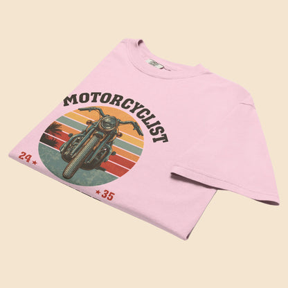 Camiseta rosa pastel doblada destacando el estampado de motocicleta retro y la caida del algodon pesado.
