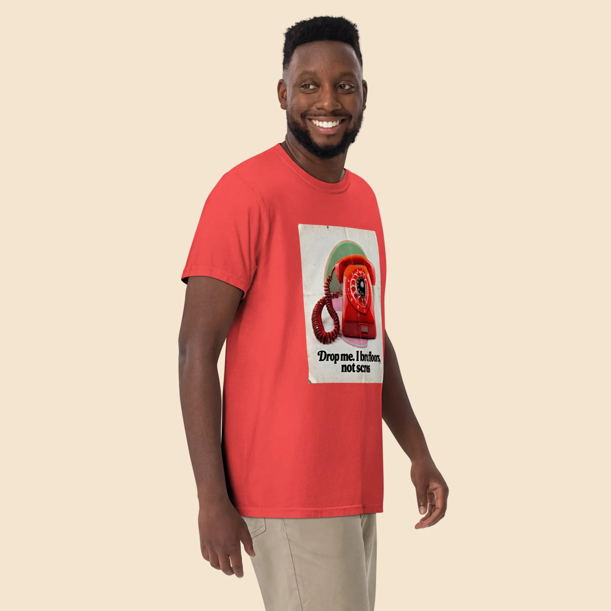 Hombre sonriendo con estilo urbano llevando una camiseta roja retro con diseño ironico sobre la tecnologia antigua.