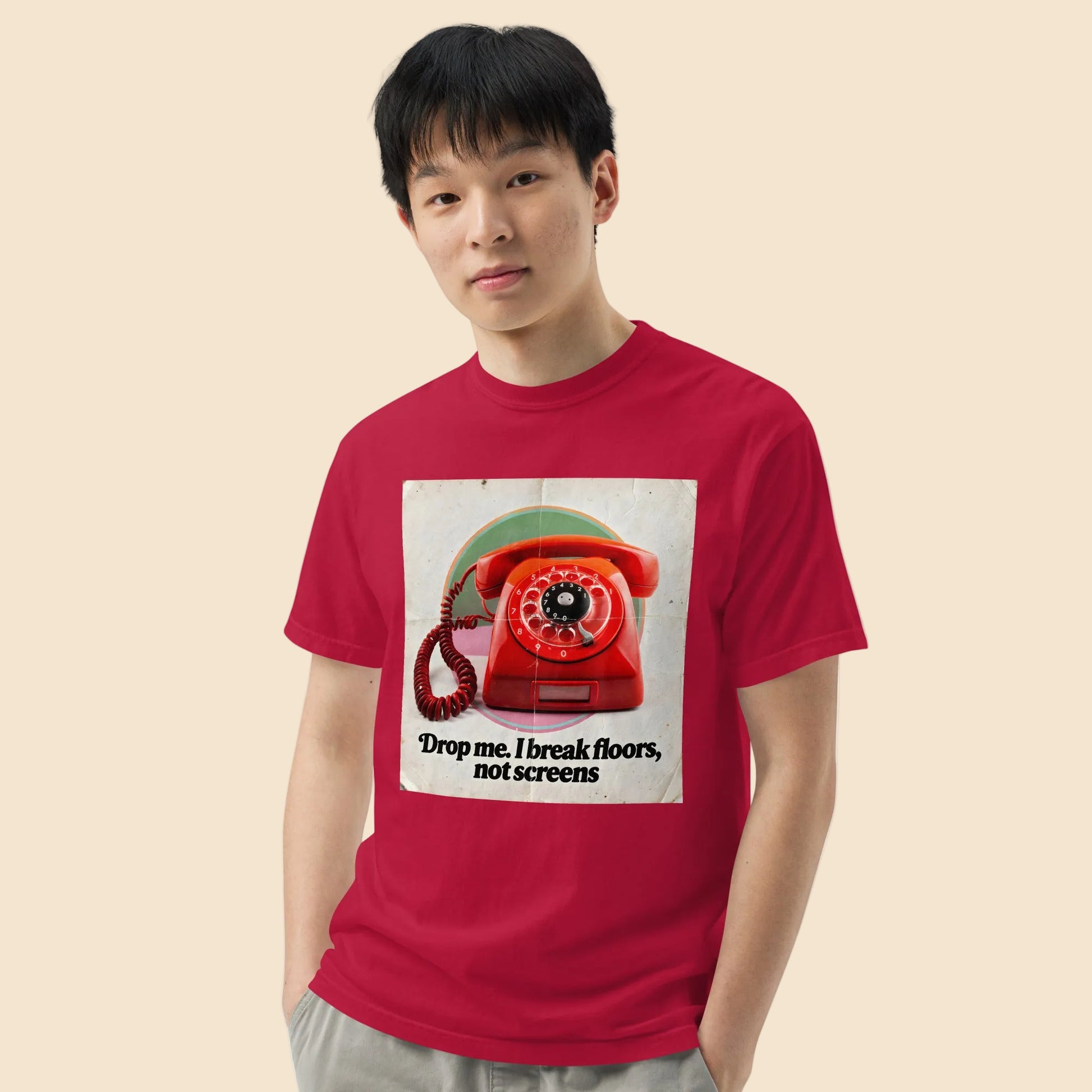 Hombre luciendo una camiseta roja de aspecto lavado con estampado retro de telefono indestructible.