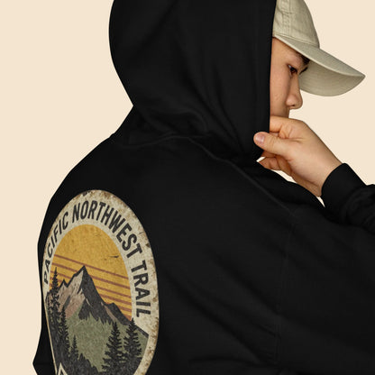 Modelo de perfil con sudadera negra y estampado vintage de naturaleza.