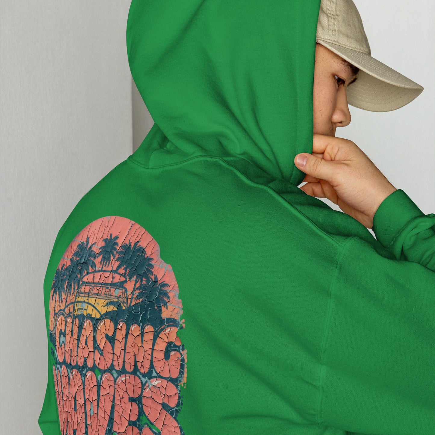 Detalle de sudadera con capucha verde luciendo gráfico retro de olas y atardecer.
