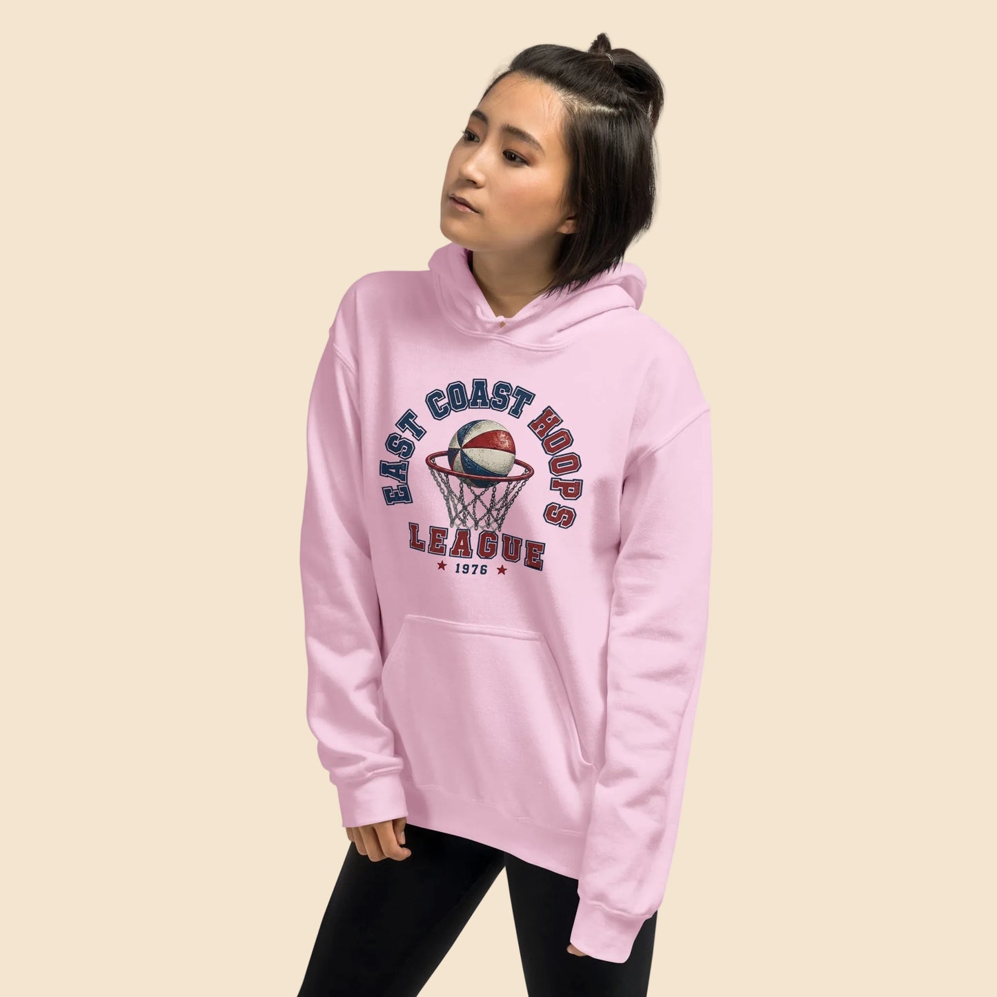  Mujer vistiendo sudadera con capucha rosa pastel con estampado deportivo vintage.