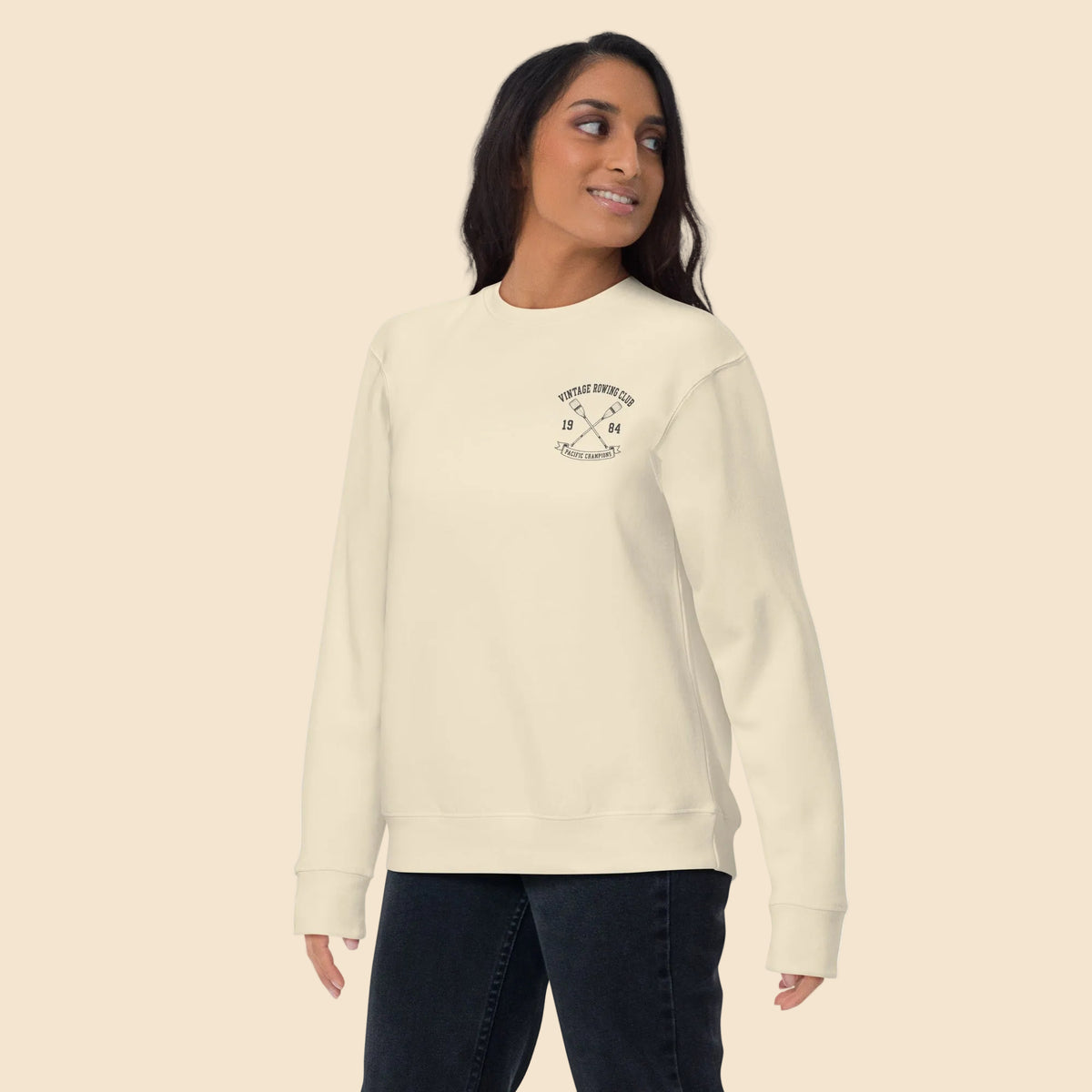 Mujer de pie con sudadera color hueso y diseño universitario retro.