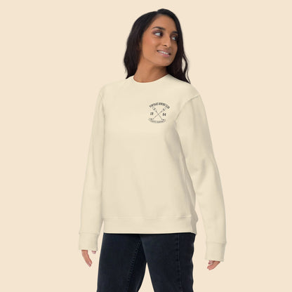 Mujer de pie con sudadera color hueso y diseño universitario retro.