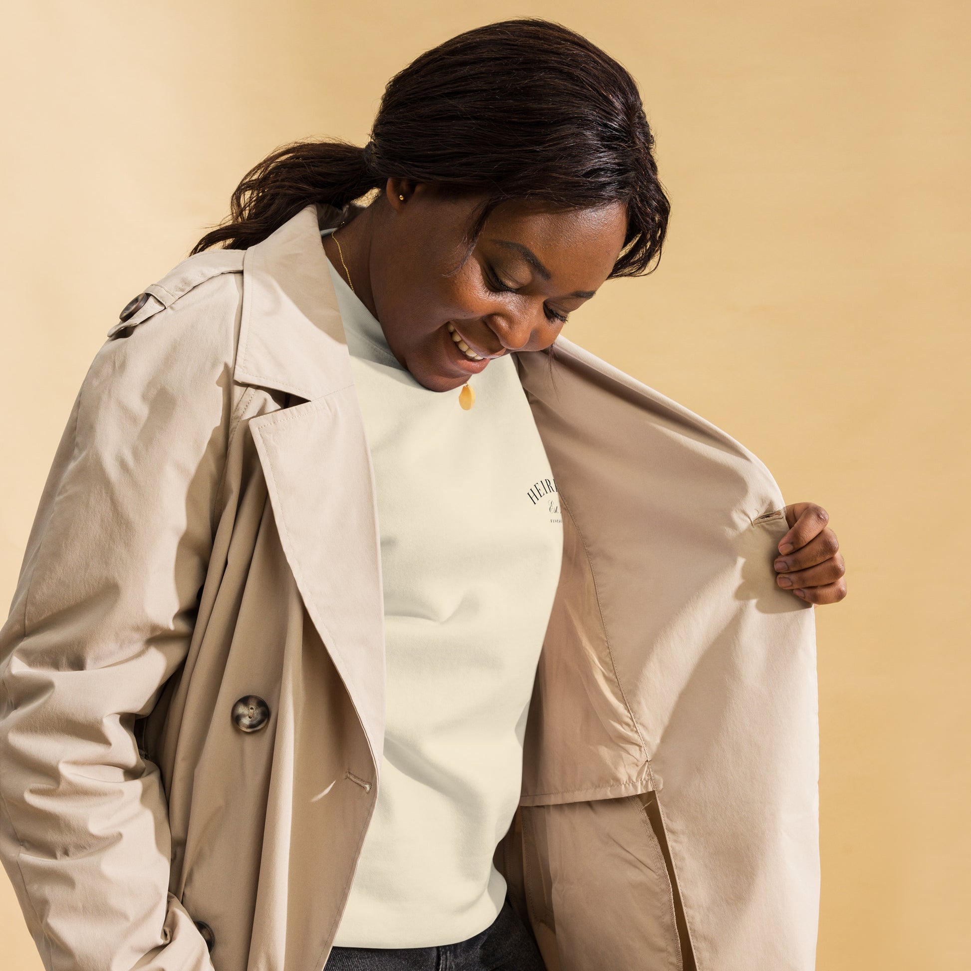 Mujer combinando sudadera premium color hueso bajo un abrigo formal.