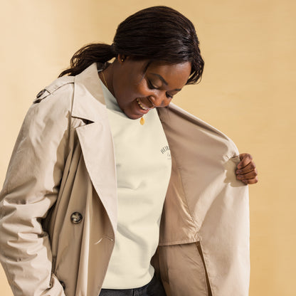 Mujer combinando sudadera premium color hueso bajo un abrigo formal.