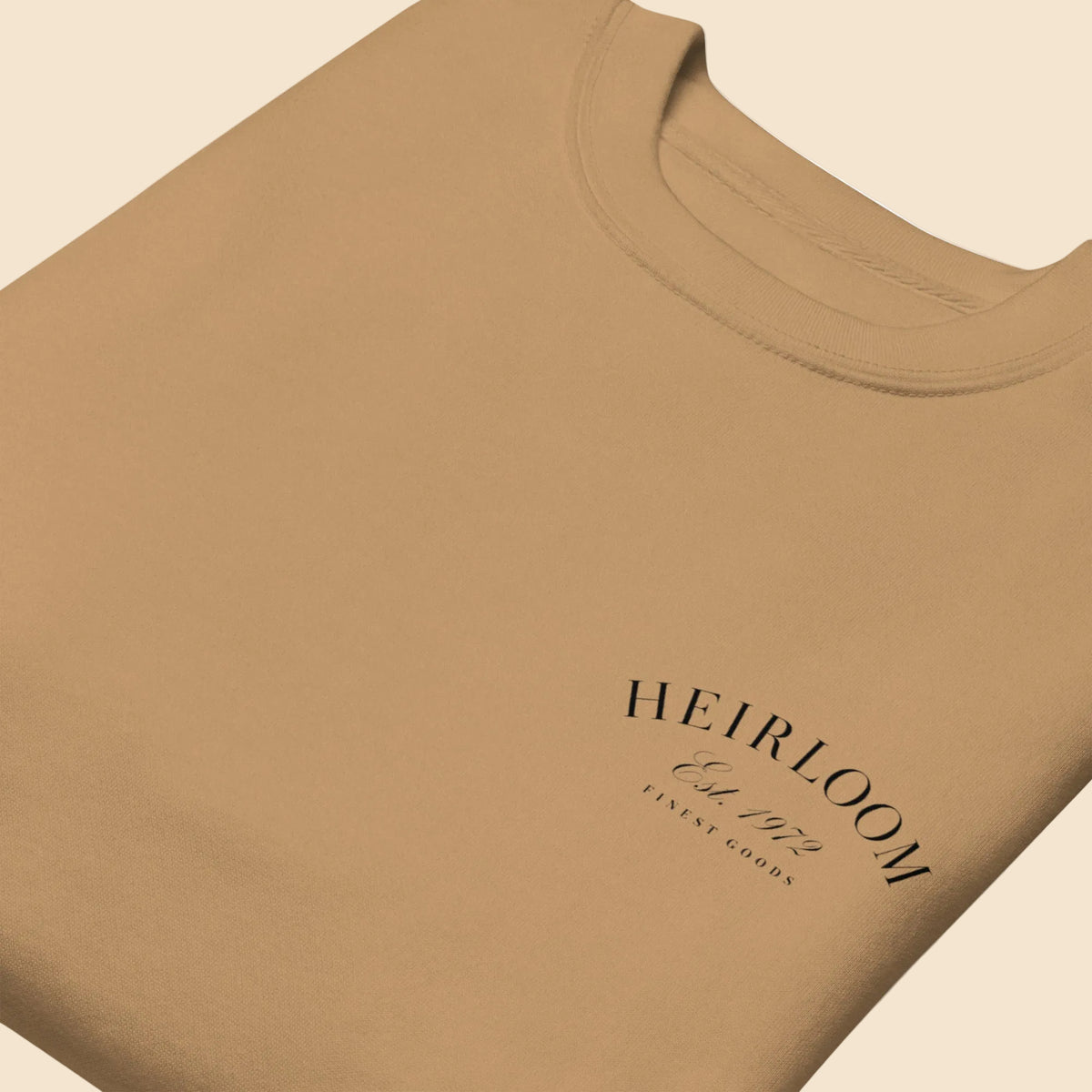 Detalle de tipografía clásica Heirloom Est 1972 Finest Goods en sudadera premium color caqui.