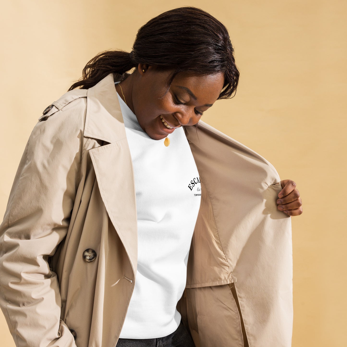 Mujer combinando sudadera premium color caqui bajo un abrigo clásico.