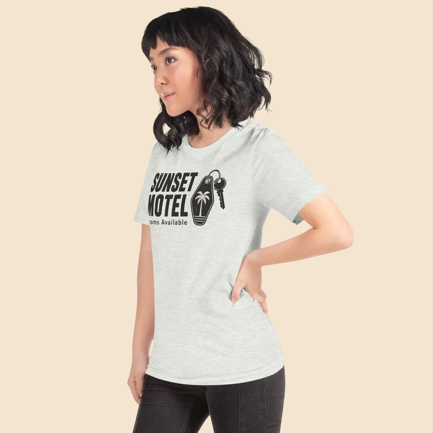 Mujer con estilo casual urbano vistiendo una camiseta blanca retro con el logo nostalgico de Sunset Motel y estetica californiana.