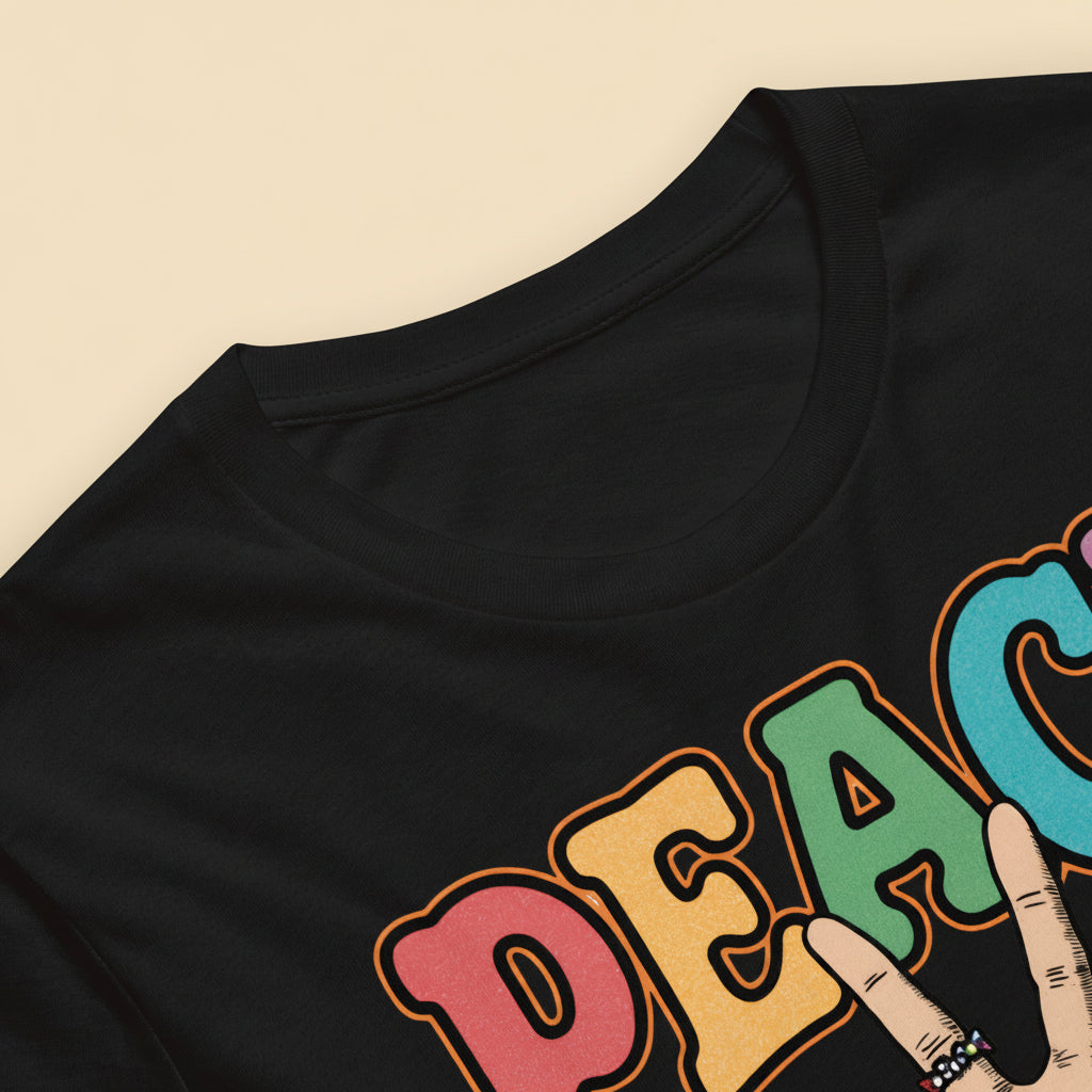 Detalle de camiseta con palabra Peace multicolor y mano haciendo el signo de la paz con estética retro