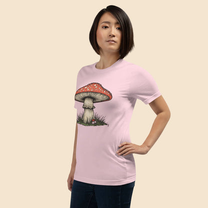 Mujer luciendo una camiseta rosa pastel suave con diseño botanico vintage de hongo rojo.