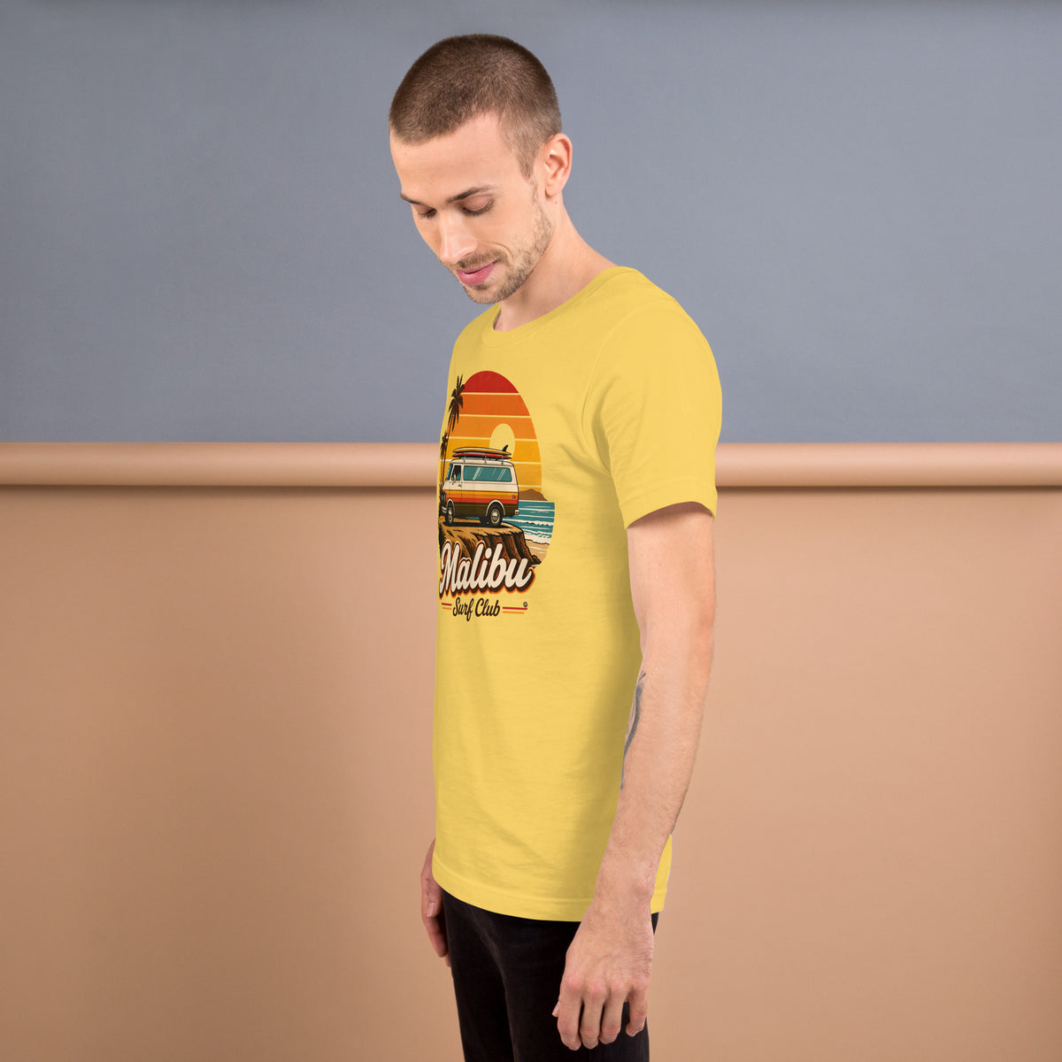 Hombre de pie con camiseta amarilla Malibu Surf Club y diseño vintage de surf y California