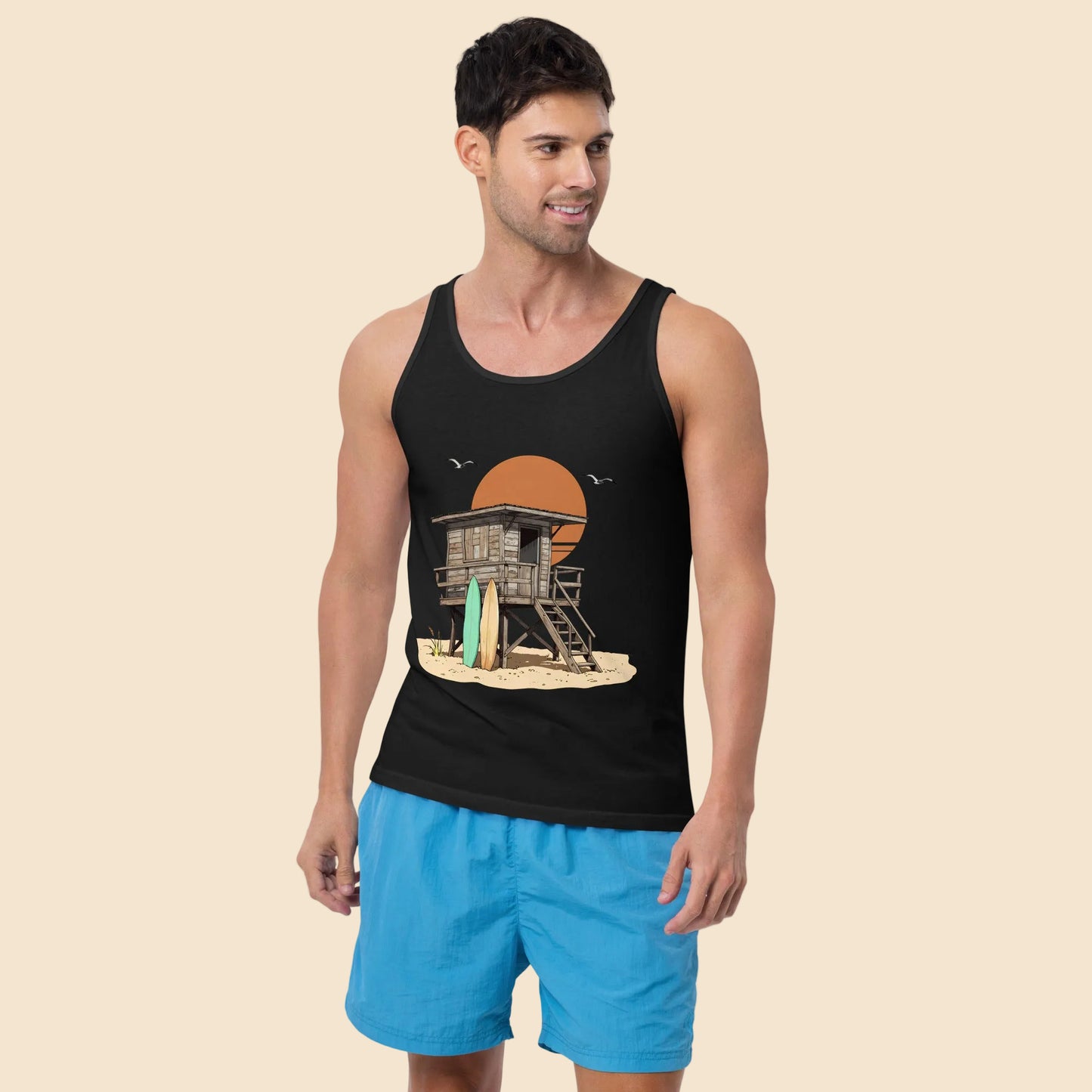 Hombre vistiendo camiseta de tirantes negra con gráfico frontal de estética californiana y caseta de madera.