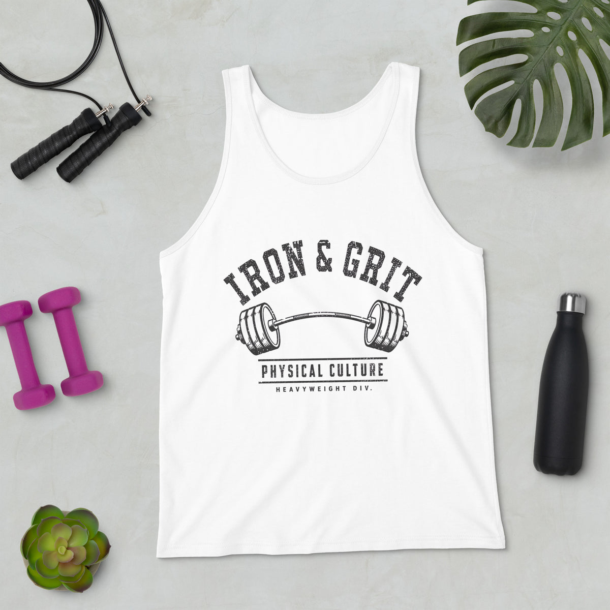 Camiseta de tirantes blanca sobre superficie plana mostrando la ilustración física Iron and Grit junto a elementos de entrenamiento.