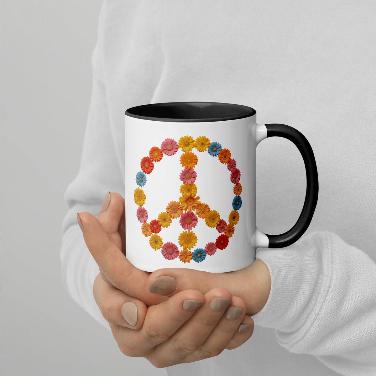 Manos de mujer sosteniendo una taza de cerámica con asa e interior negro y gráfico floral pacifista.