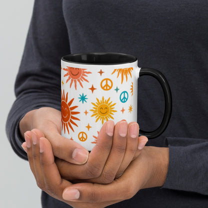 Persona sujetando taza de cerámica con estampado hippie de soles y símbolos de paz en colores cálidos.