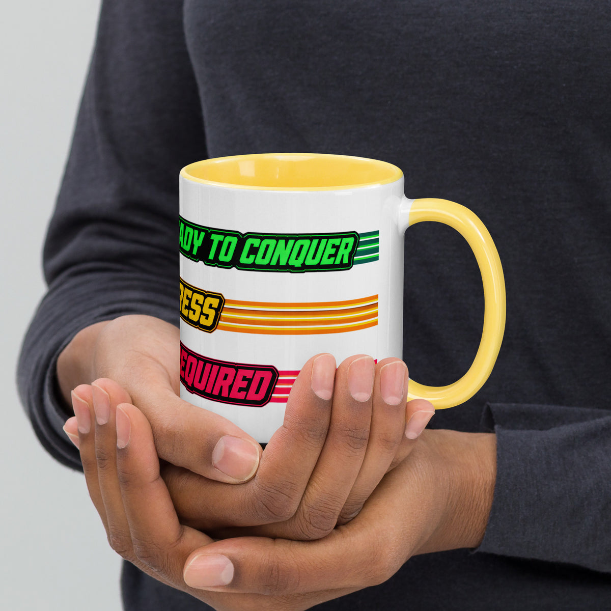 Persona sujetando taza vintage de interior amarillo con diseño de batería y estética arcade retro.